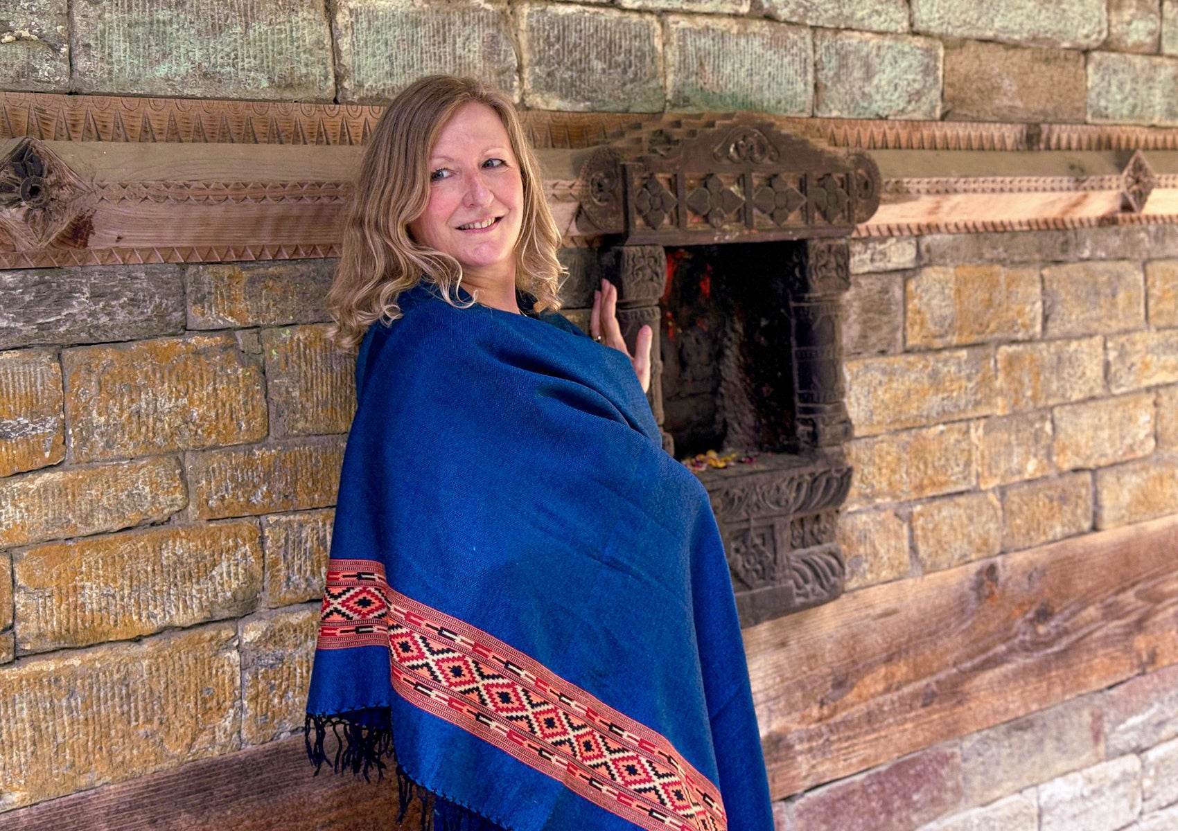 Élégant châle DEVA bleu royal en pure laine mérinos, drapé autour d’une femme dans la cour d’un temple.