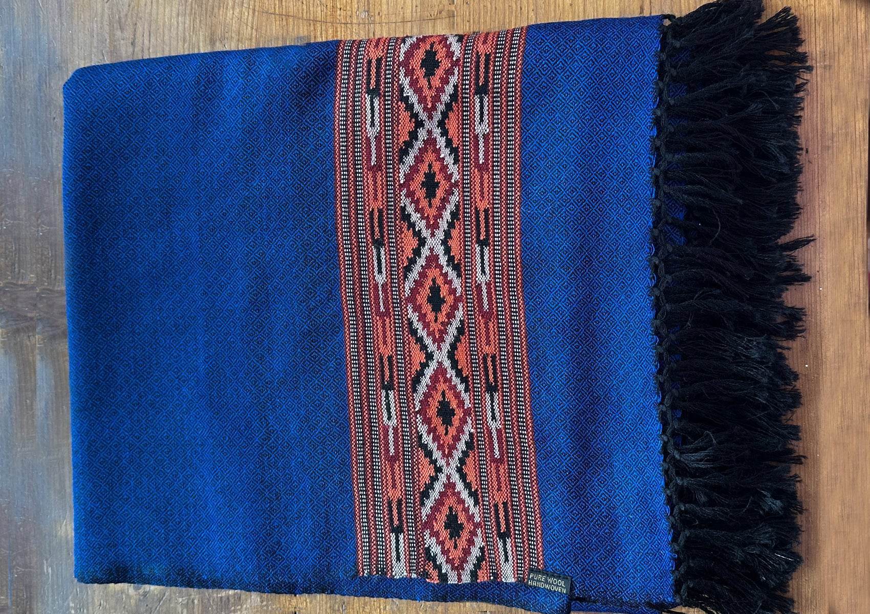 Gros plan du châle DEVA bleu royal montrant la texture fine de la laine mérinos et la bordure tissée traditionnelle.