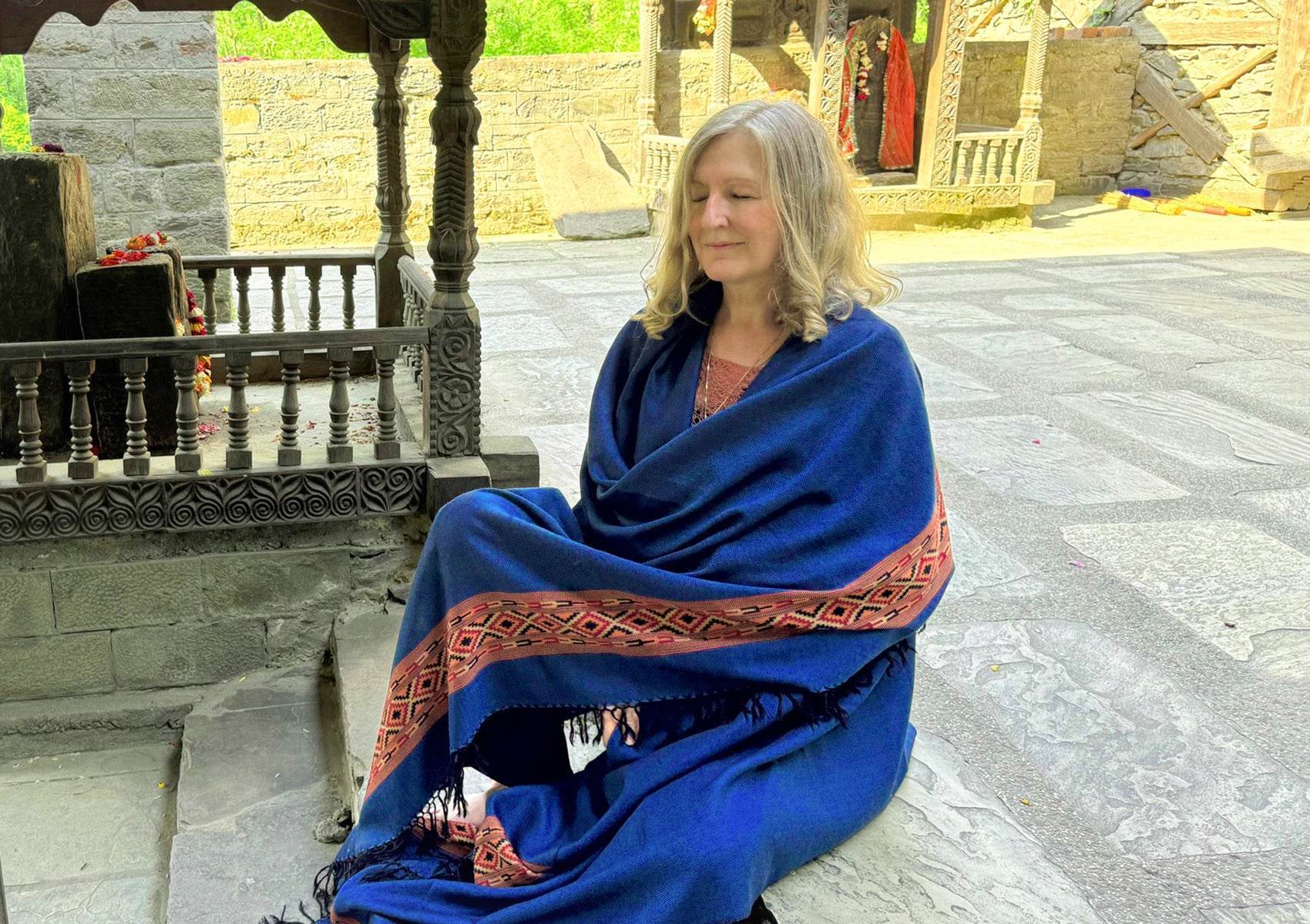 Femme méditant dans un temple himalayen portant le châle DEVA bleu royal en laine mérinos