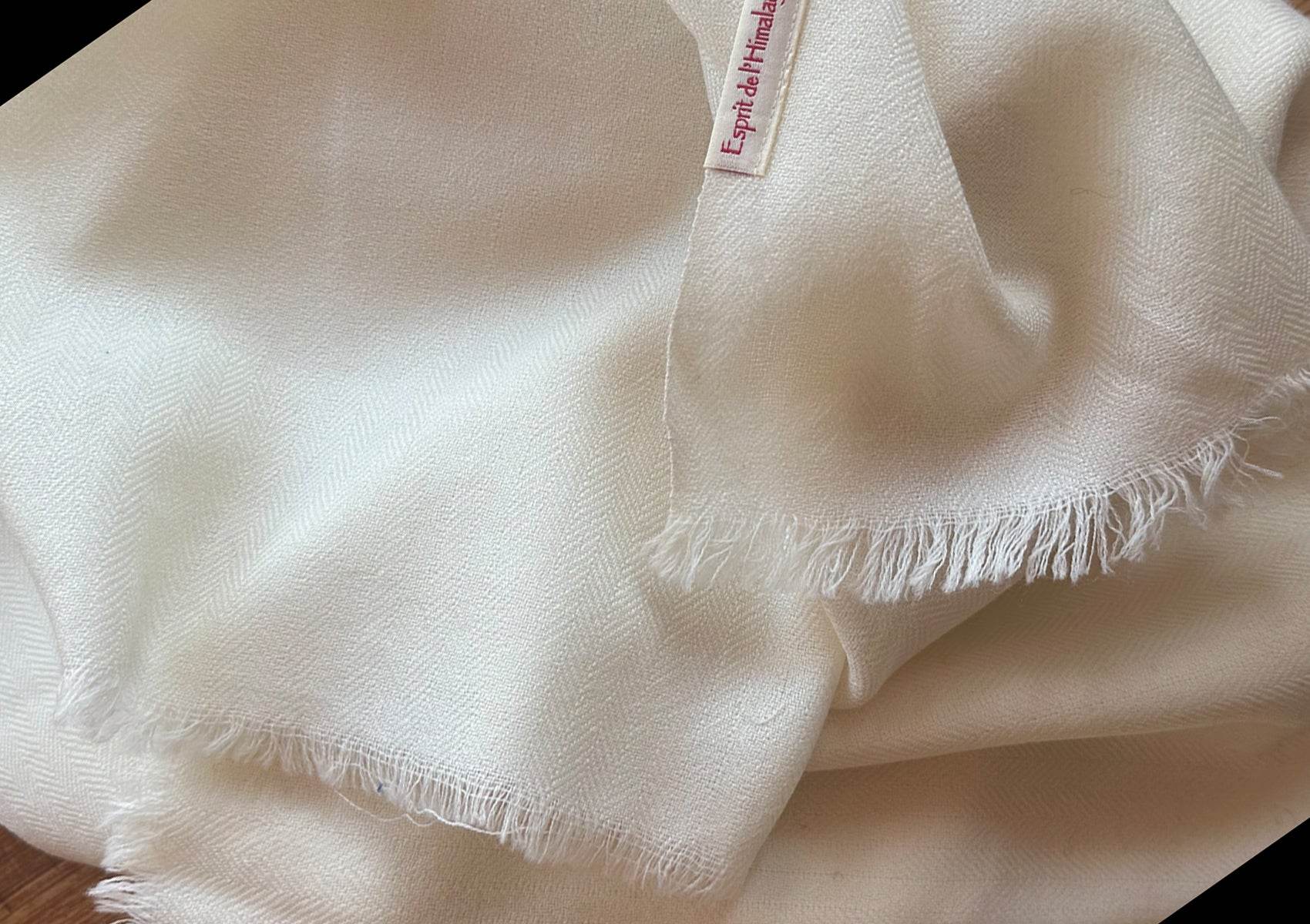 Close-up of fine herringbone weave on a cream merino wool lama shawl, showing soft texture and craftsmanship.