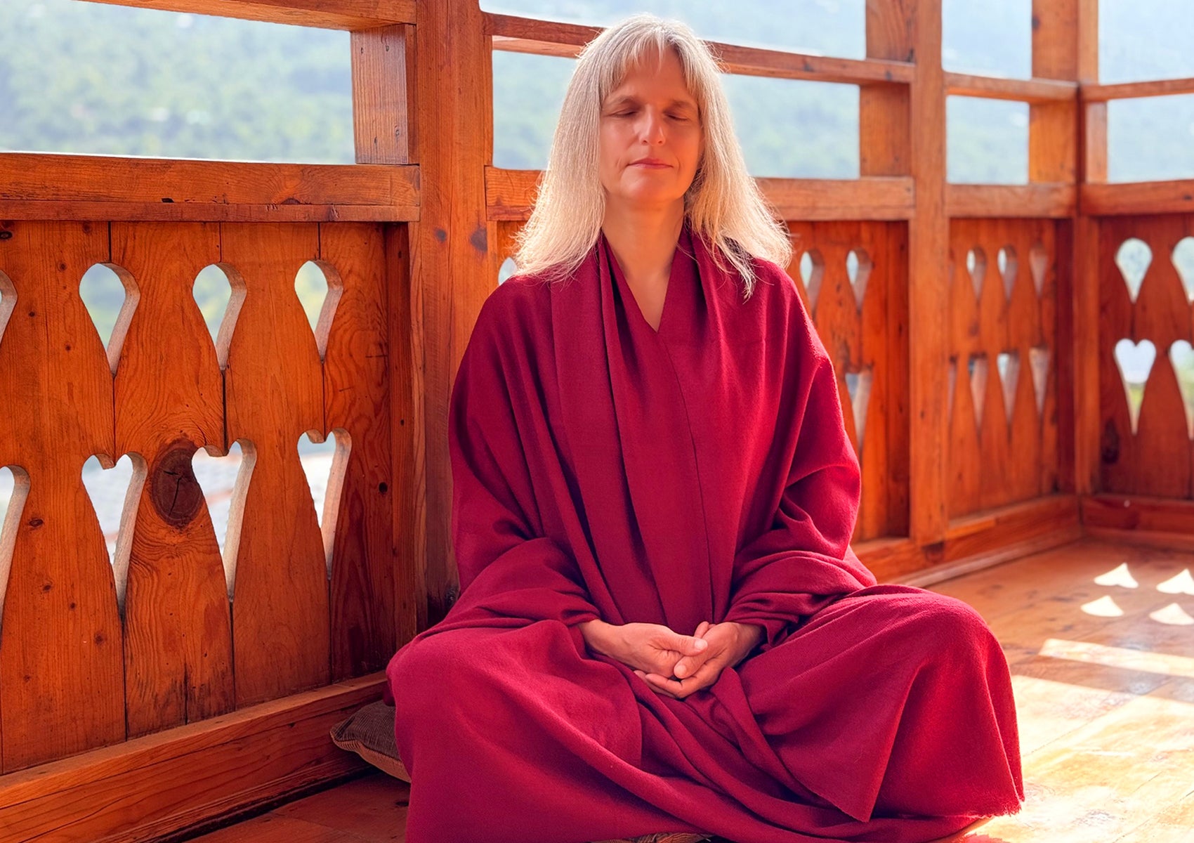 Woman sitting cross-legged wearing a LAMA burgundy meditation shawl, ideal as a Tibetan shawl or lama shawl.
