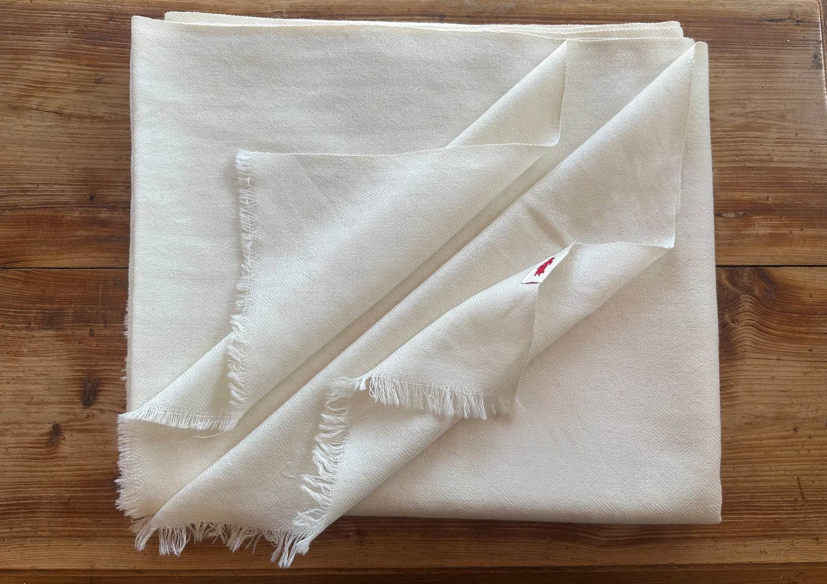 Close-up of cream lama meditation shawl showing fine merino wool fibers and intricate herringbone weave pattern.