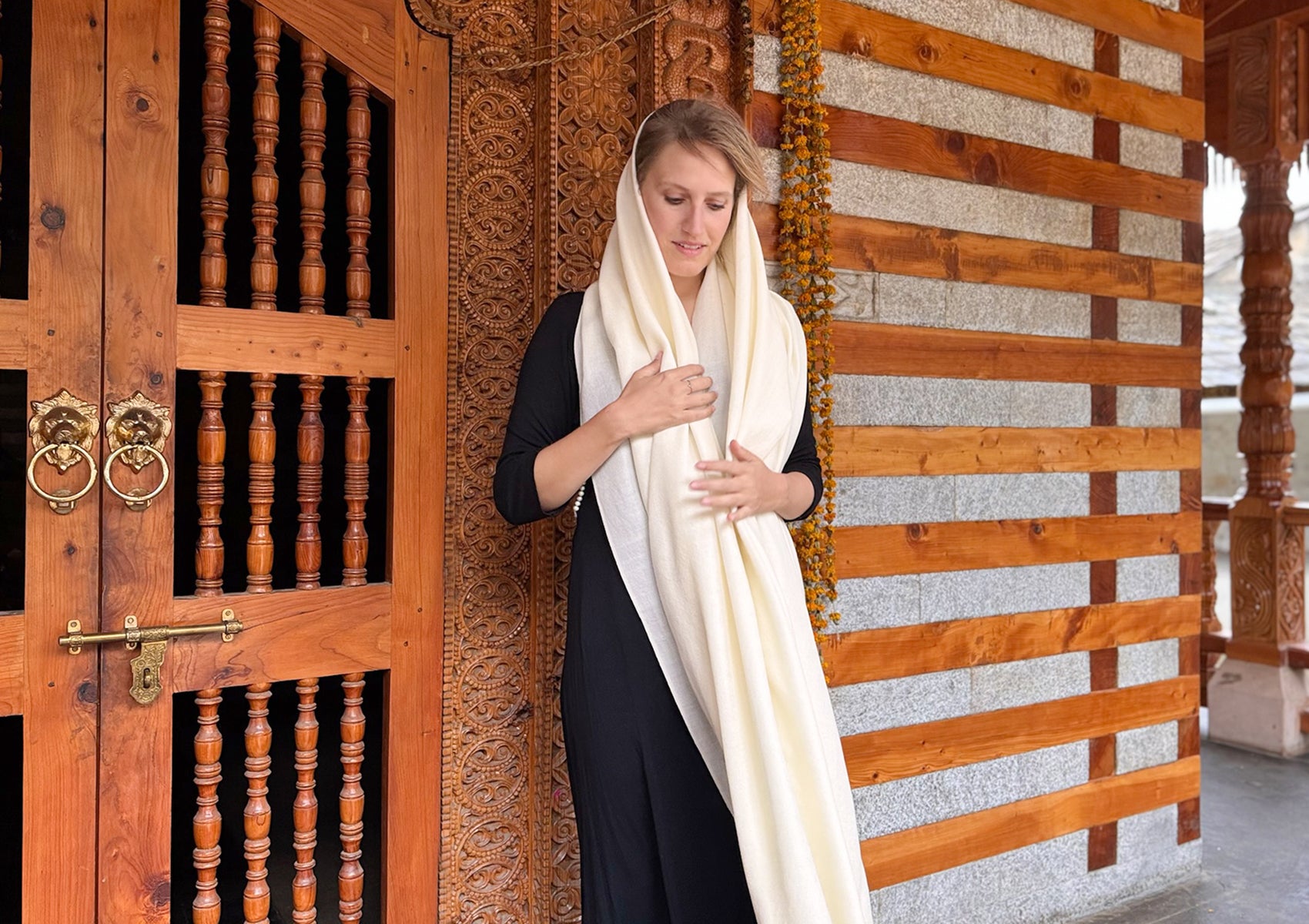 Woman gracefully spreading the cream meditation shawl outside a Himalayan temple