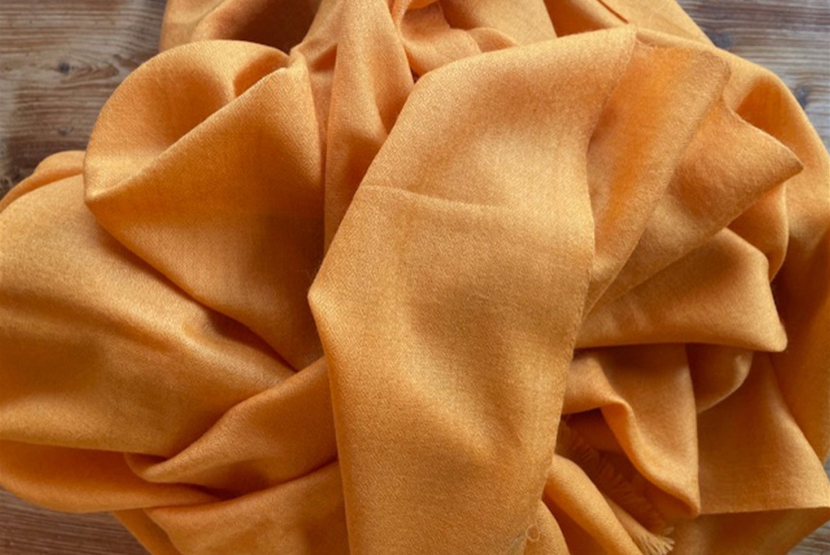 Orange shawl fabric arranged in a bundle, capturing its plush and comfortable texture.