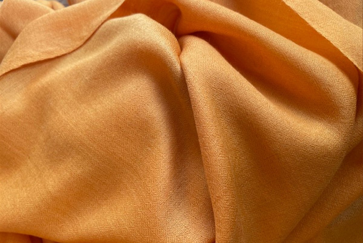 Bright orange shawl fabric, showing its smooth texture and comfortable drape.