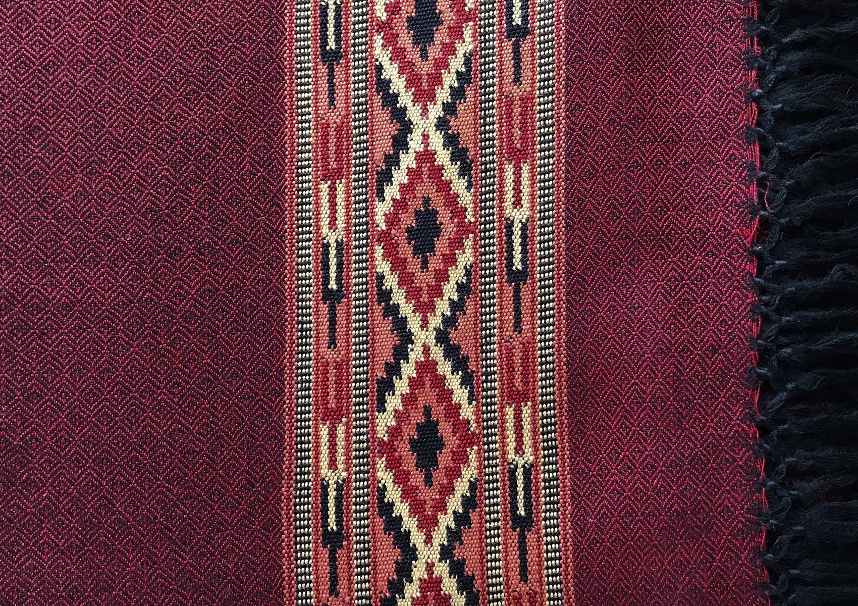 Detailed view of DEVA dark red merino wool meditation shawl showing traditional woven ethnic border.