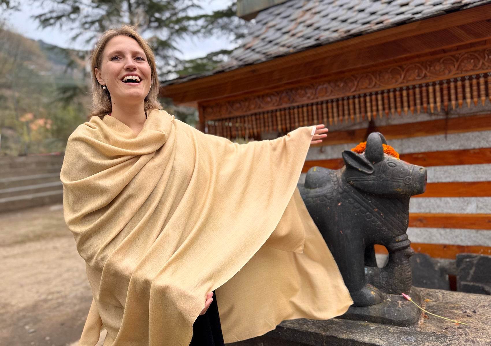 9. Smiling woman wrapped in Shunyata beige shawl, Himalayan temple background.