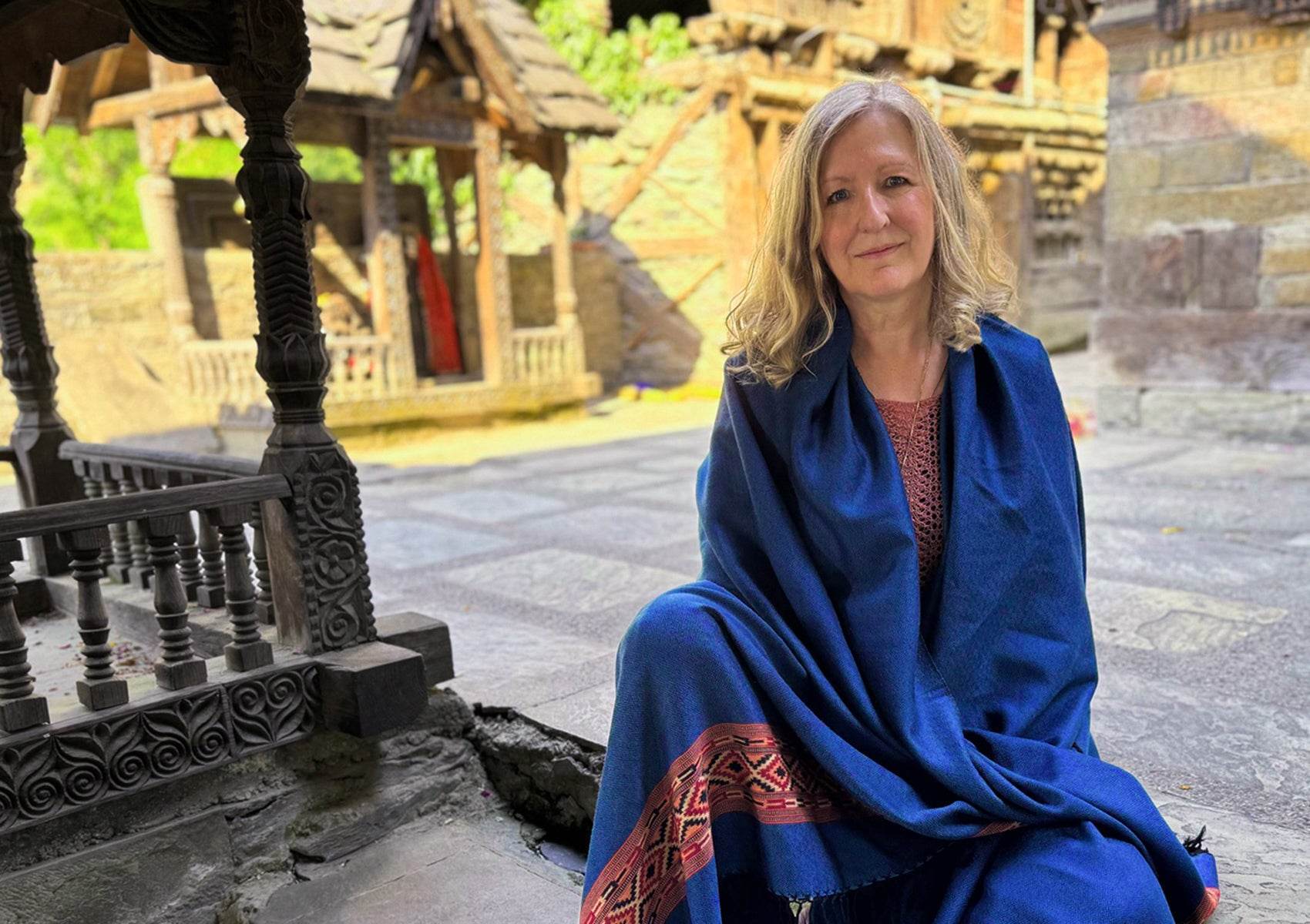 Grand châle DEVA bleu royal en laine mérinos pour la méditation, présenté dans un cadre de temple himalayen.