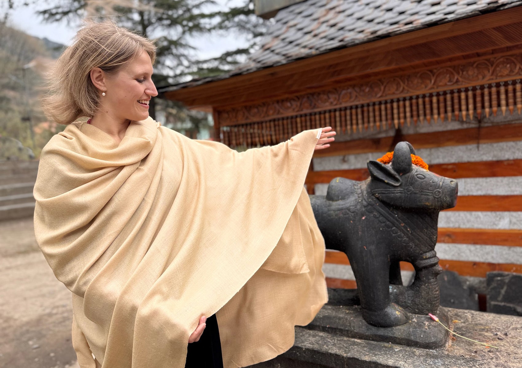 Handwoven beige merino meditation shawl in front of a serene temple wall