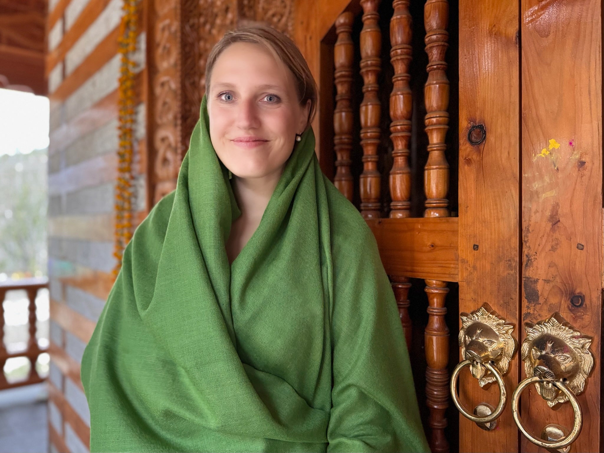 Woman meditating at a temple entrance covered in fern green shawl
