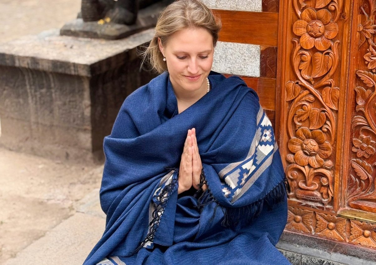 Portrait of a woman wearing the Mahadev Shawl by Esprit de l’Himalaya, handwoven blue wool with border.