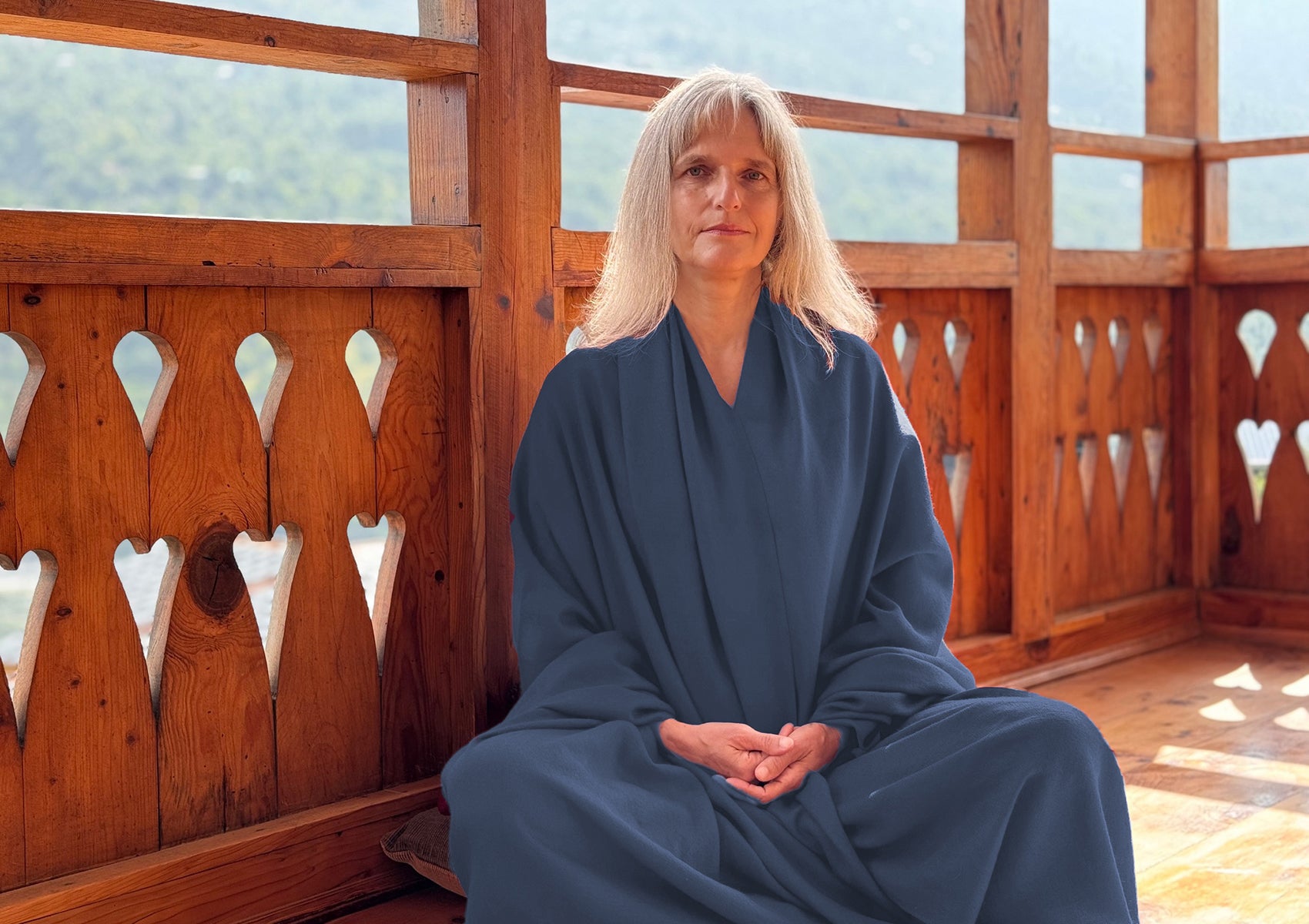 Woman meditating on a wooden balcony wearing the LAMA steel blue wool shawl.