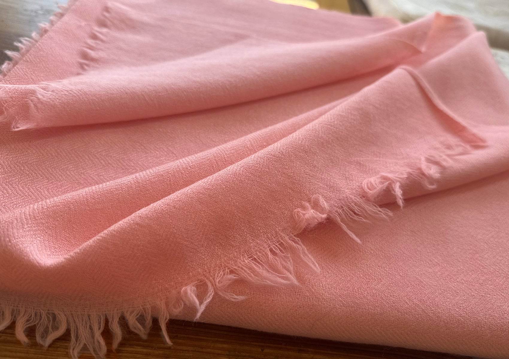 Close-up of peach LAMA Tibetan shawl showing the detailed diamond weave texture.
