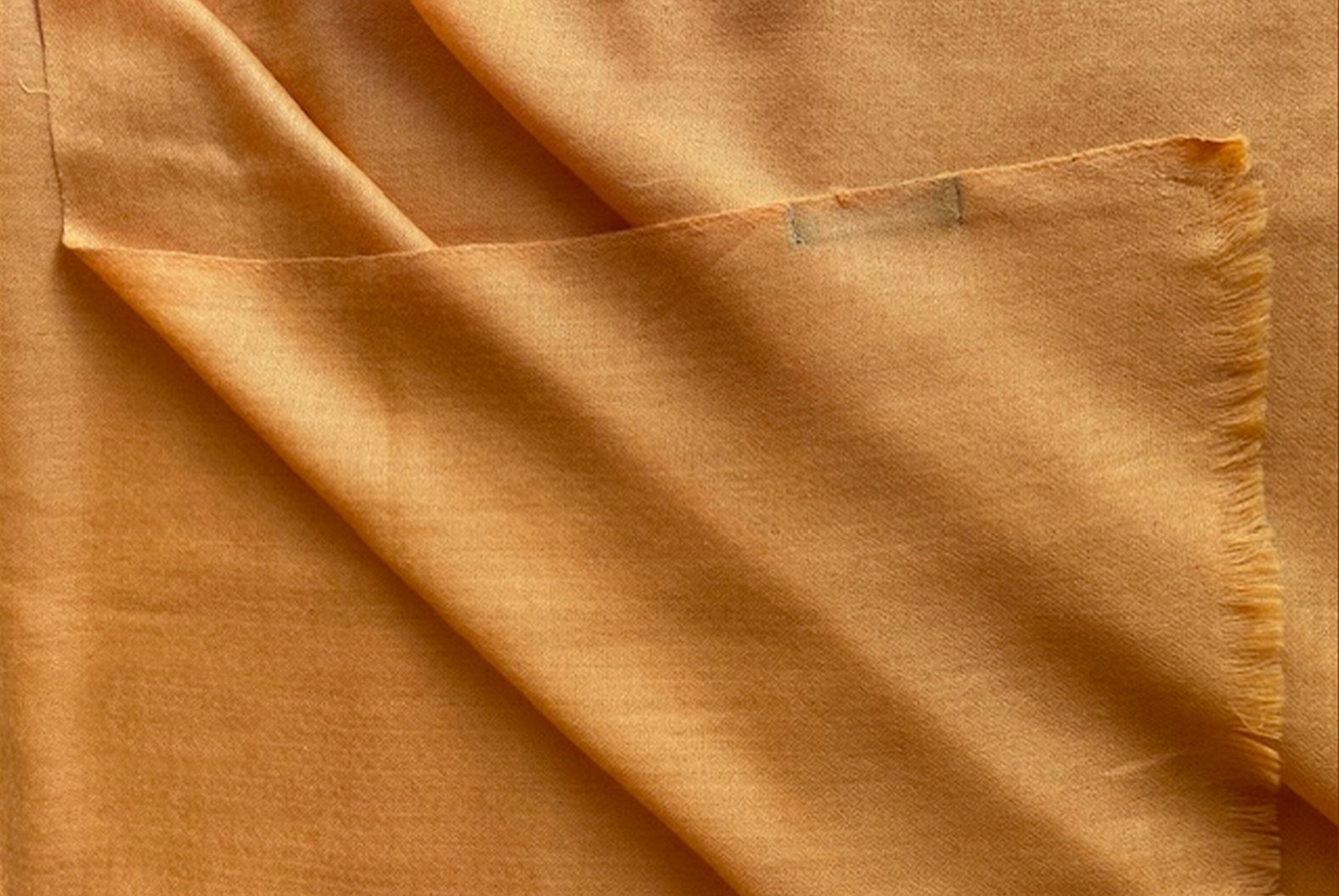 Close-up of an orange shawl showing the delicate, lightweight fabric perfect for relaxation.