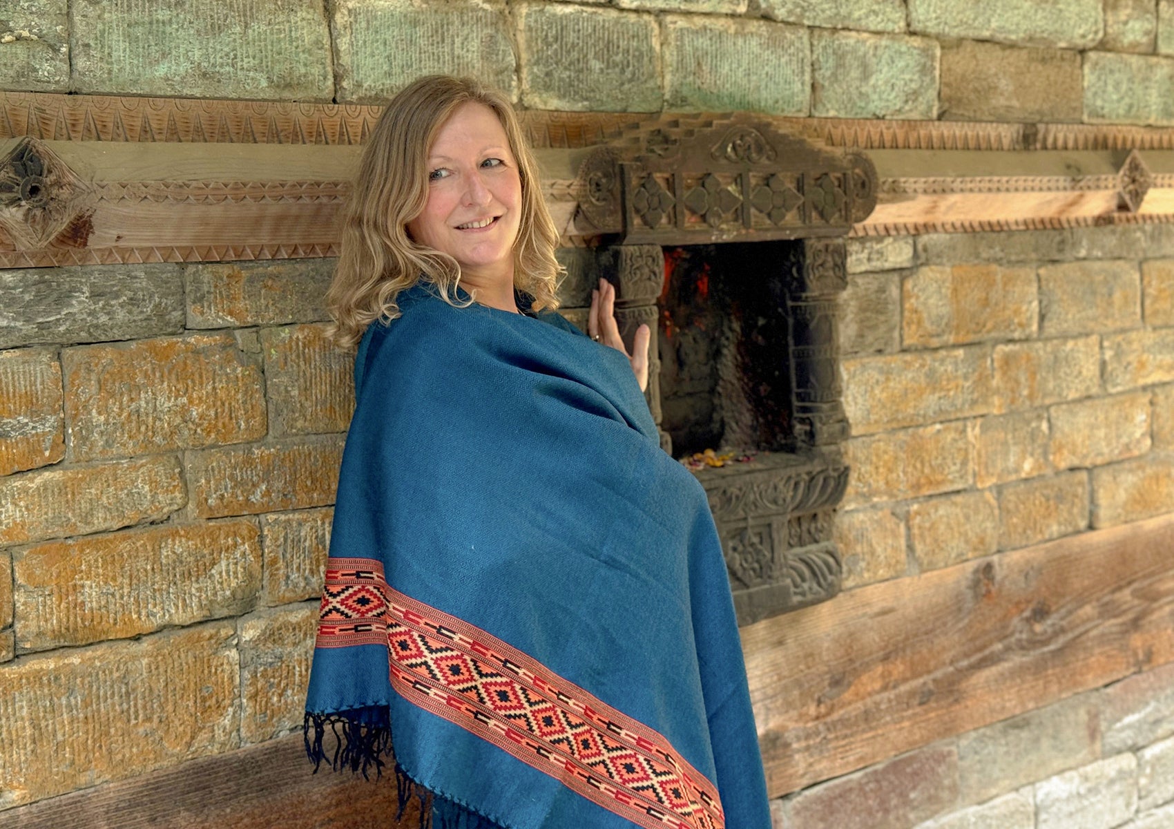 Close-up of DEVA denim blue merino wool meditation shawl with traditional woven border and fringes.