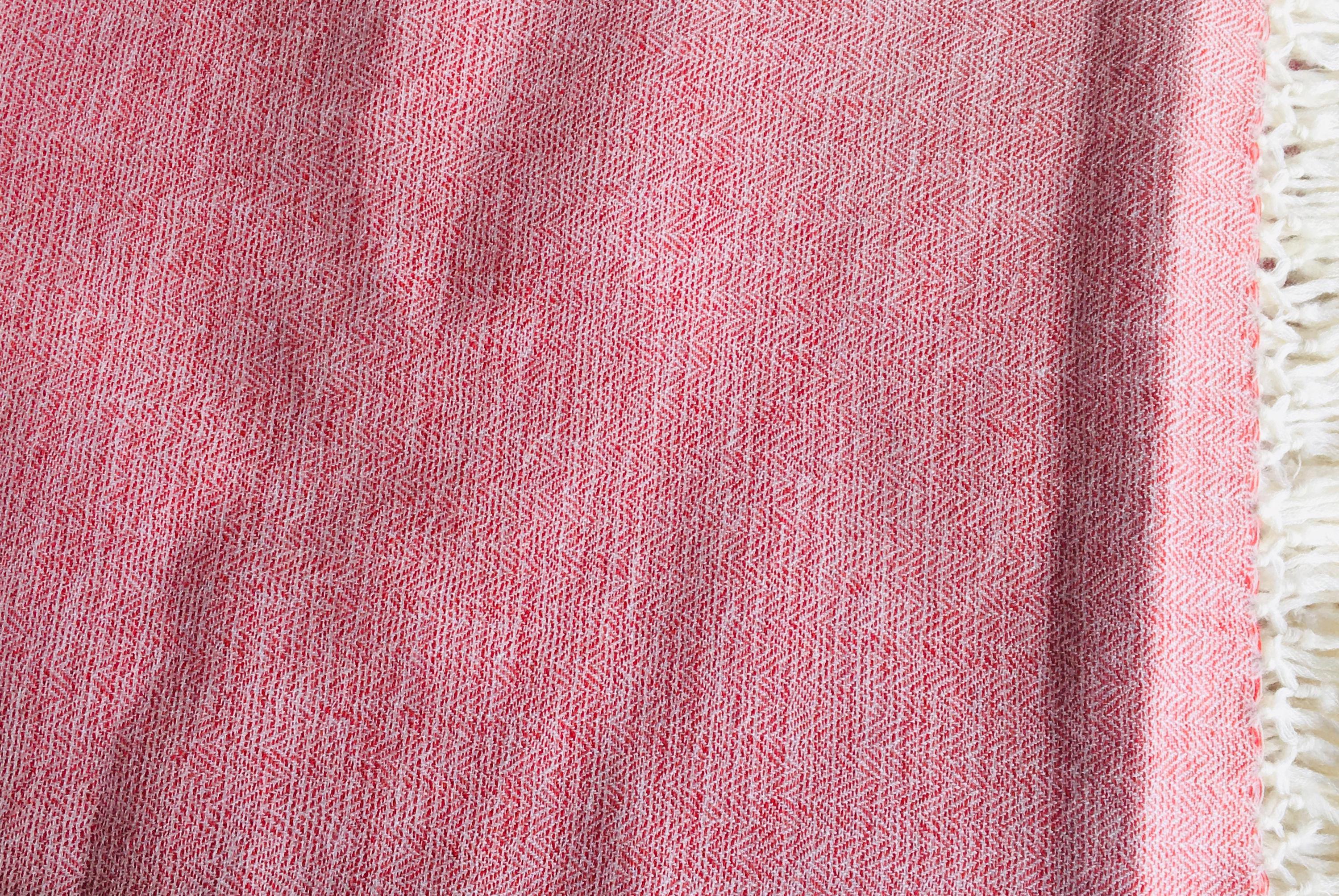 Close-up of a pink shawl, showcasing the texture and pattern of the woven fabric.